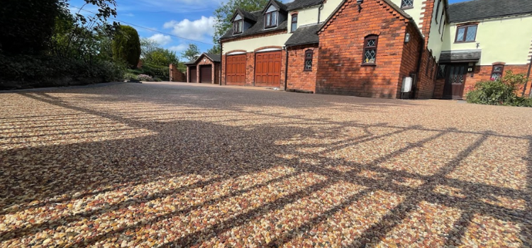 A homeowner looking at the new resin driveway that has just been installed next to their large house upping their curb appeal