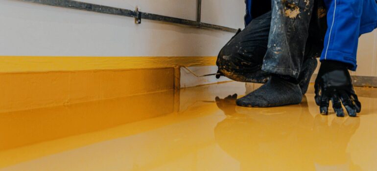 Man laying a resin floor, showing the durability Of Industrial Resin Flooring across different industries