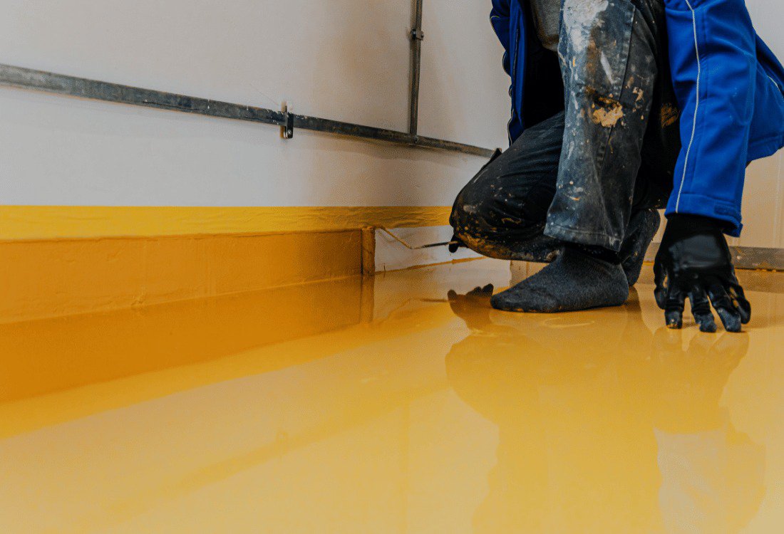 Man laying a resin floor, showing the durability Of Industrial Resin Flooring across different industries