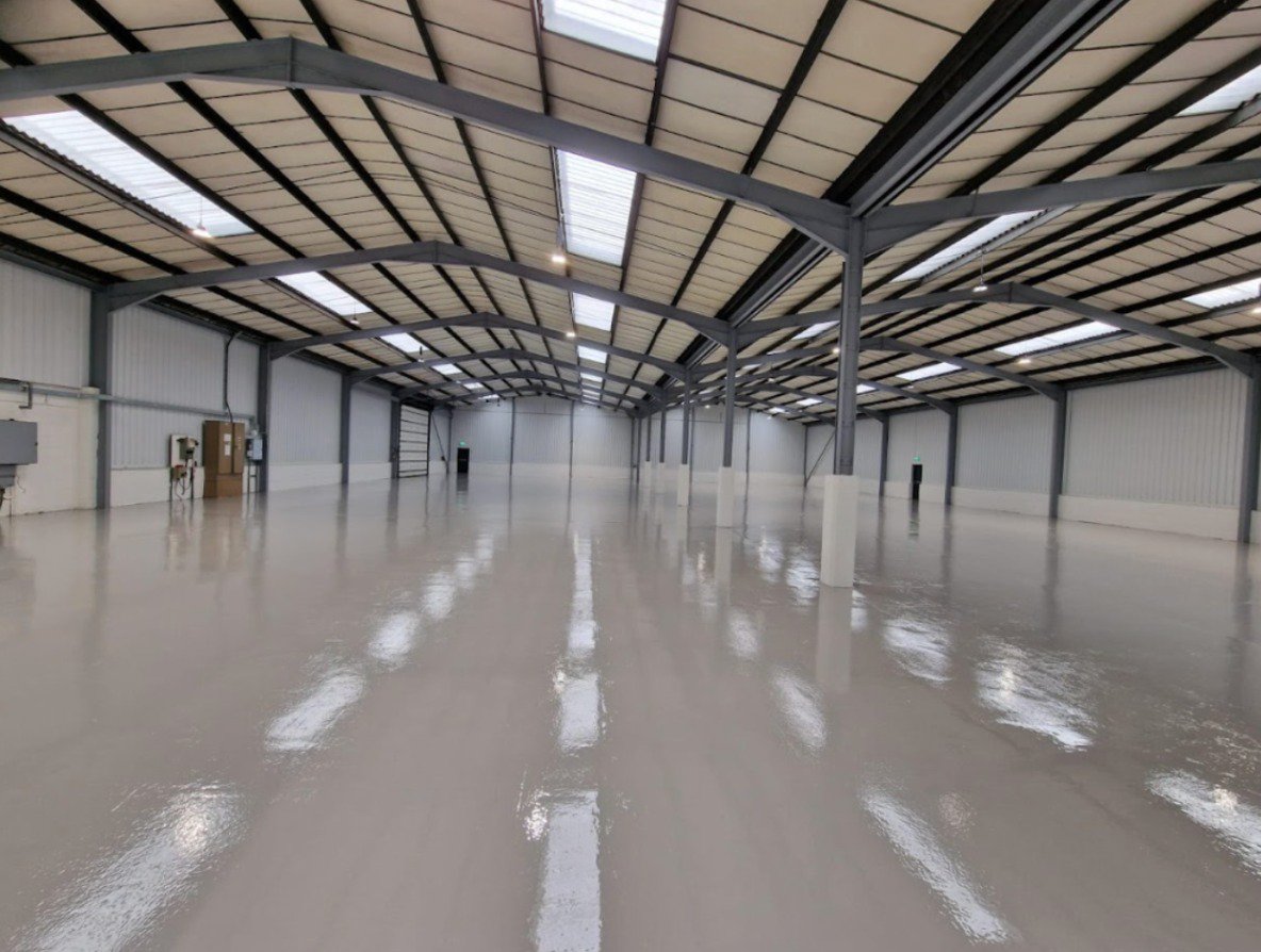 An empty warehouse with fresh off-white epoxy resin showing the advantages of warehouse epoxy resin.