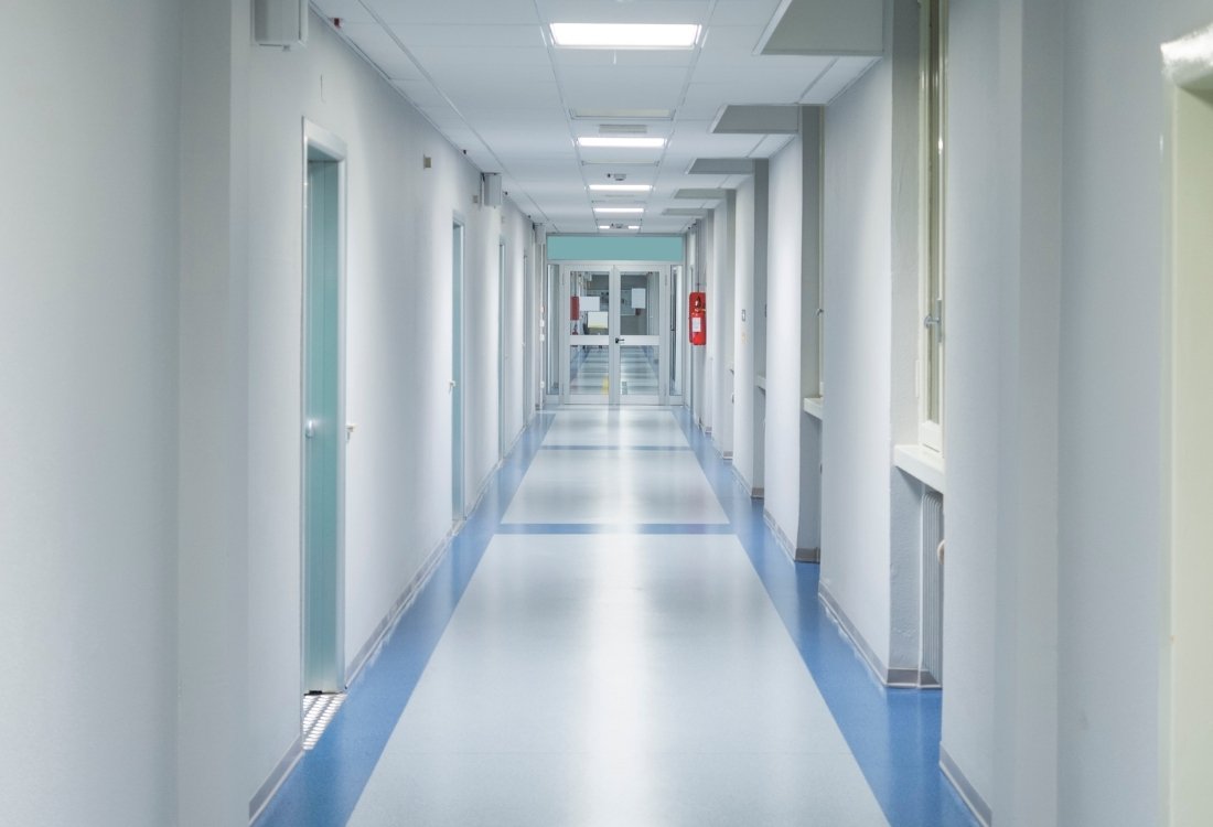 Bright hospital corridor with smooth blue and white flooring, designed for easy cleaning and hygiene in medical environments.