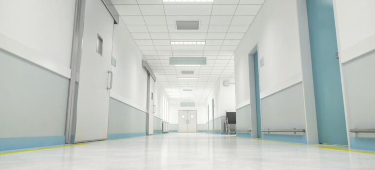Clean and bright hospital corridor with polished floors, white walls, and blue doors, illustrating hygienic and durable flooring for medical facilities.