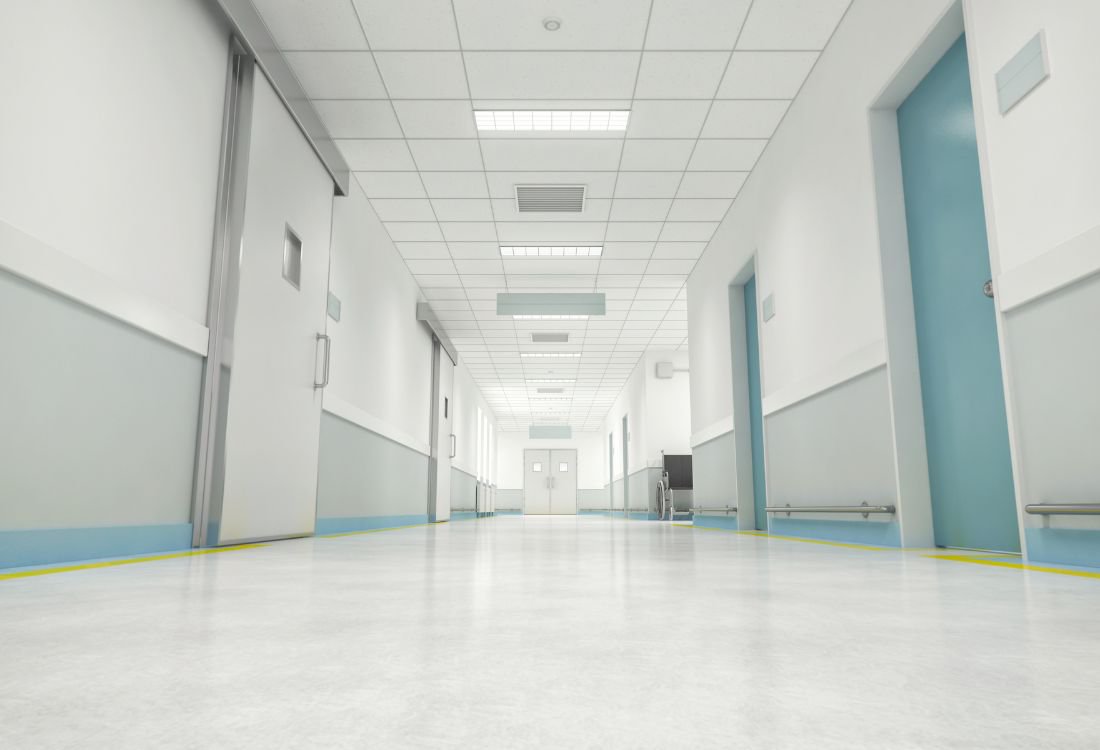 Clean and bright hospital corridor with polished floors, white walls, and blue doors, illustrating hygienic and durable flooring for medical facilities.