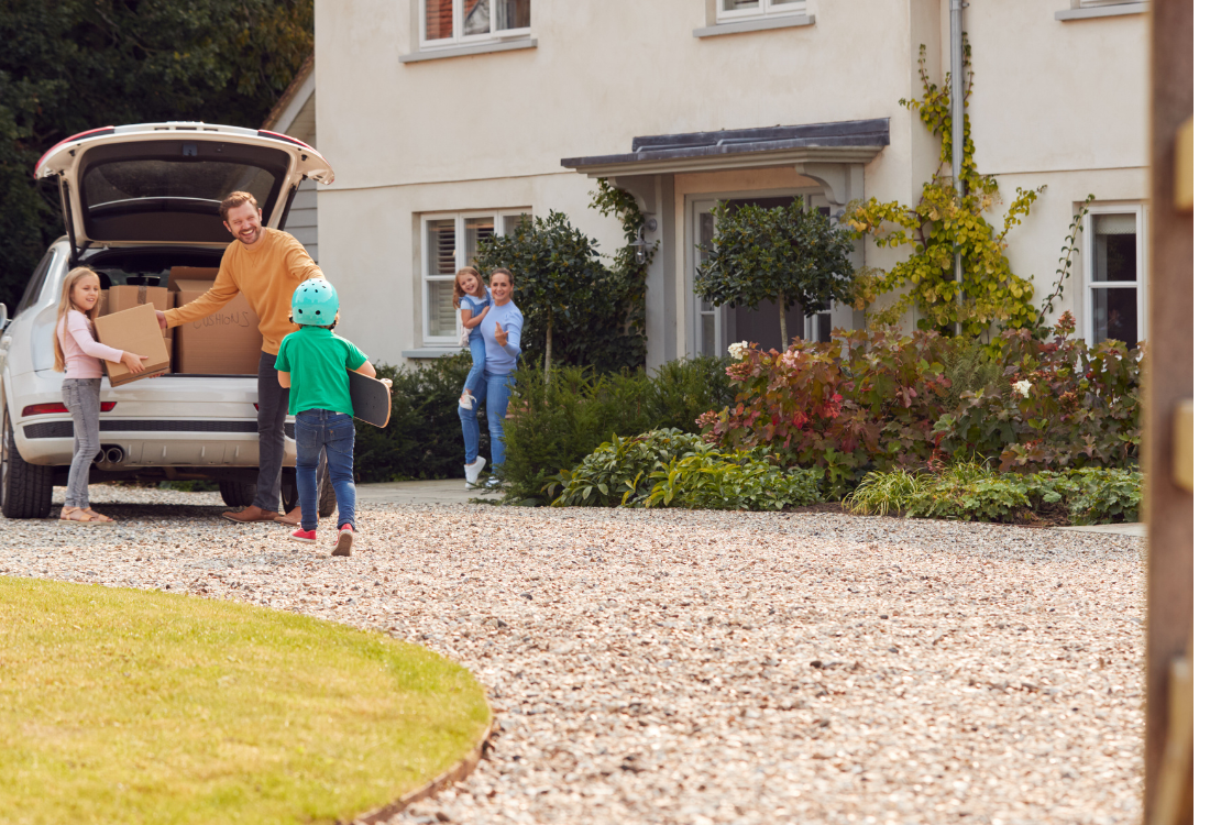 A happy family outside their home with a resin driveway, highlighting the practical benefits and kerb appeal of investing in a resin bound driveway in 2026.