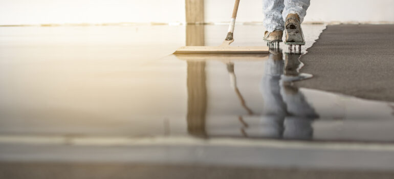 Retail worker cleaning polished commercial flooring, showcasing epoxy floor benefits including easy maintenance, hygiene and long-term durability.